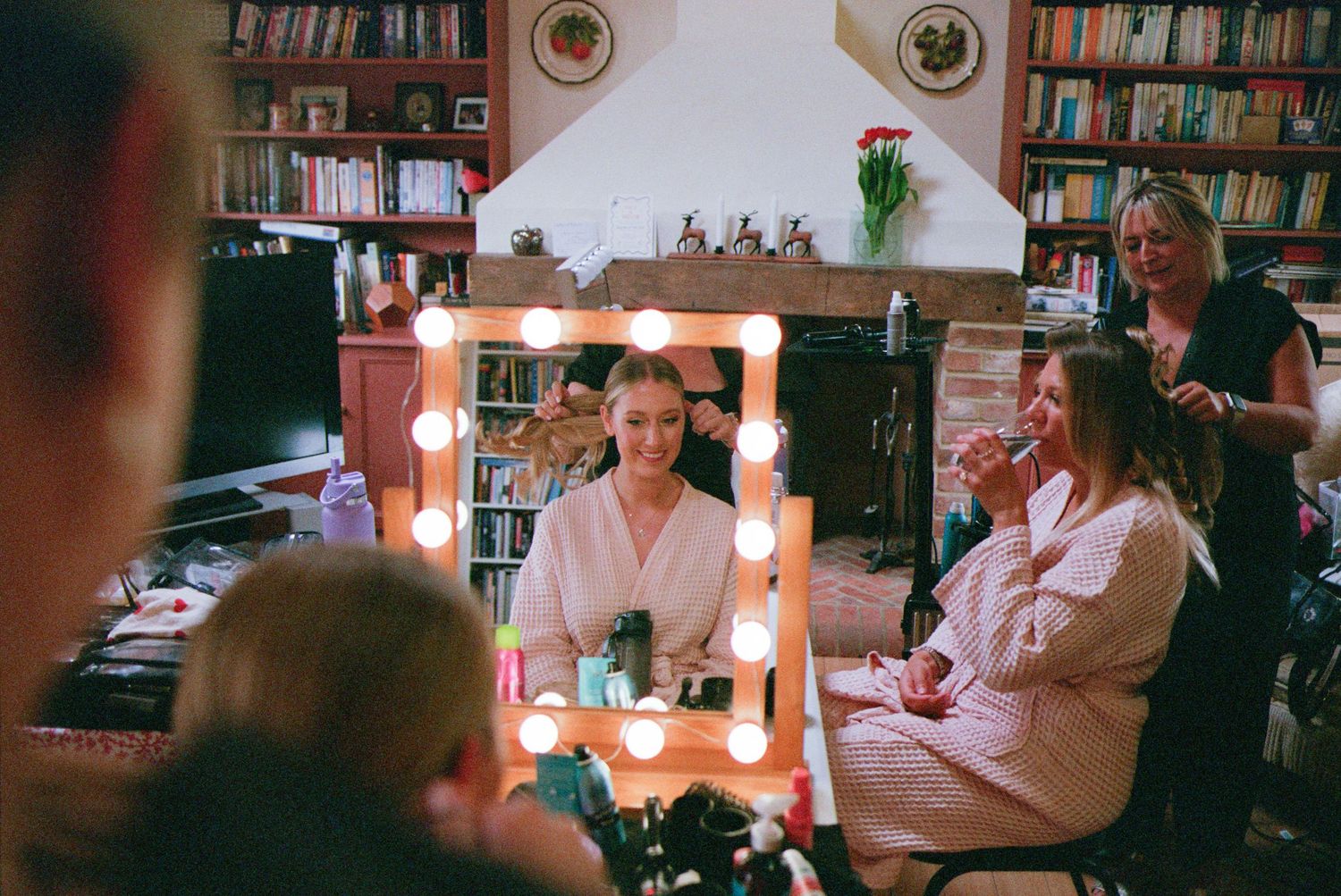 A candlelit evening scene shows people comfortably gathered together in a dimly lit room with bookshelves.