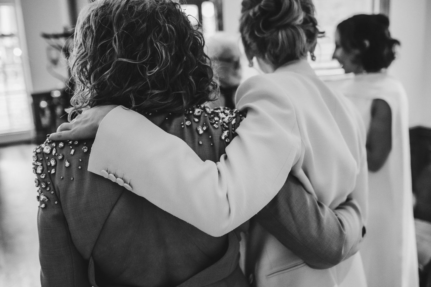 Black and white photo of two people embracing in formal attire.