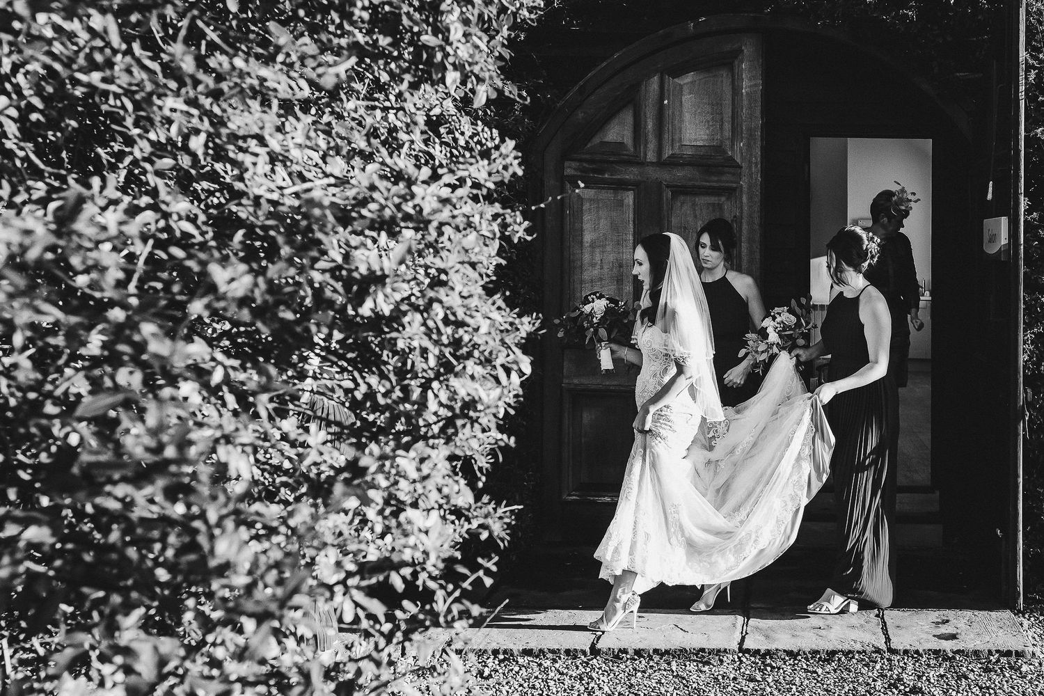 Black and white photo of wedding party making dramatic exit from venue.