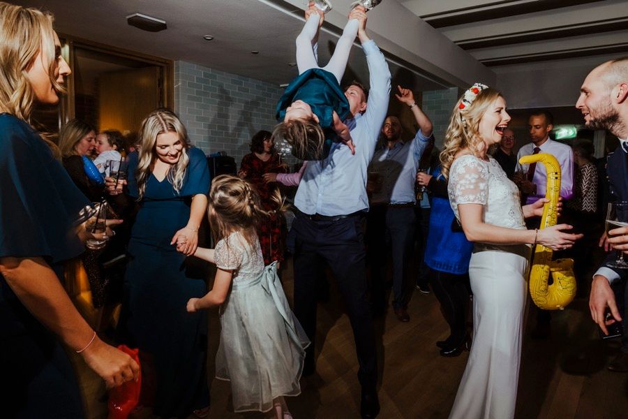 Wedding reception dance floor with guests celebrating in dimly lit venue.