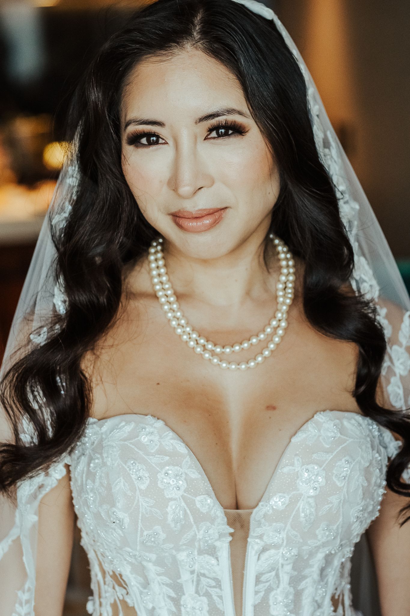 Close up portrait of bride wearing pearl necklace and lace wedding gown.