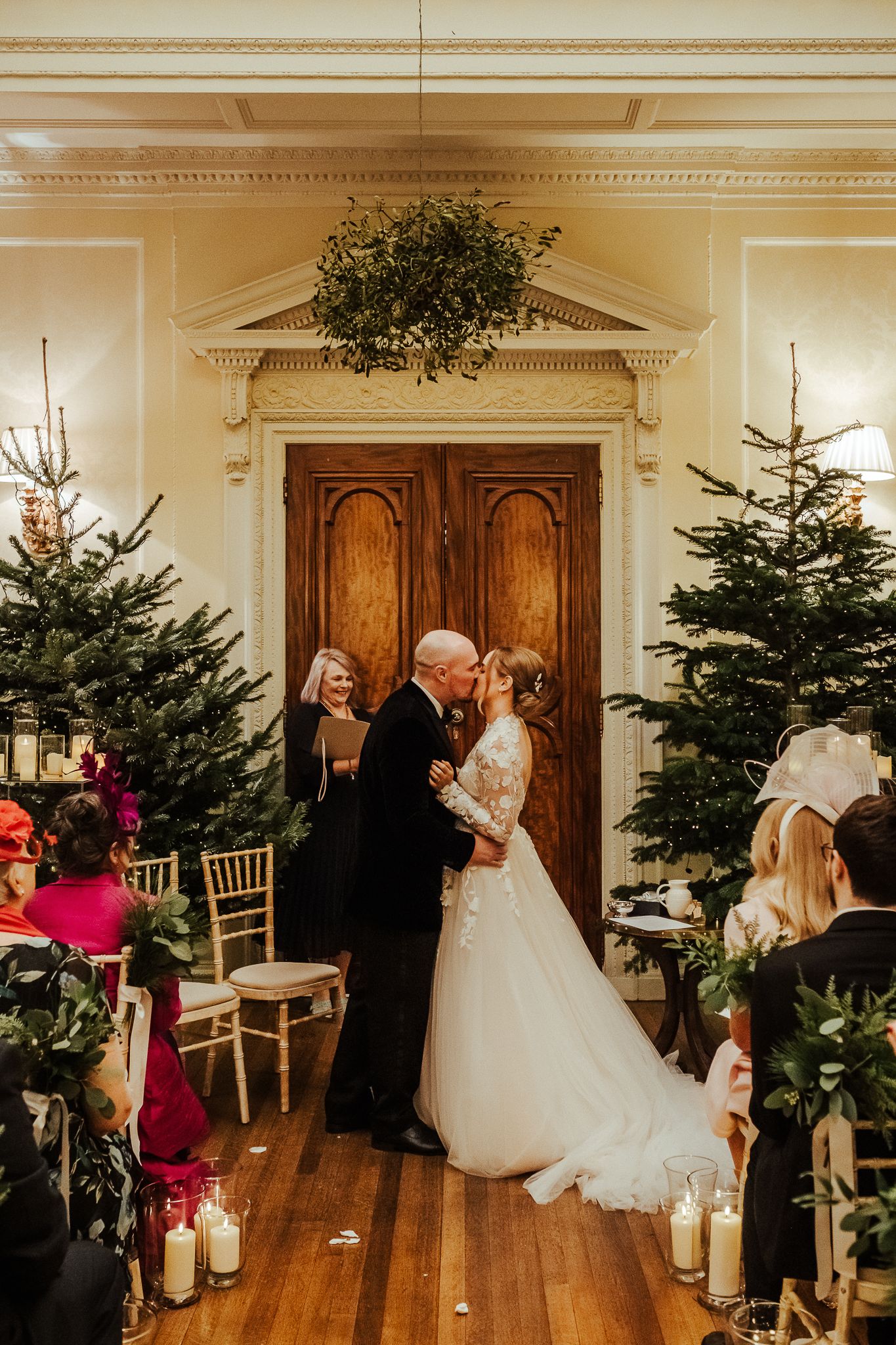Winter wedding ceremony with evergreen trees and candlelight in elegant venue.