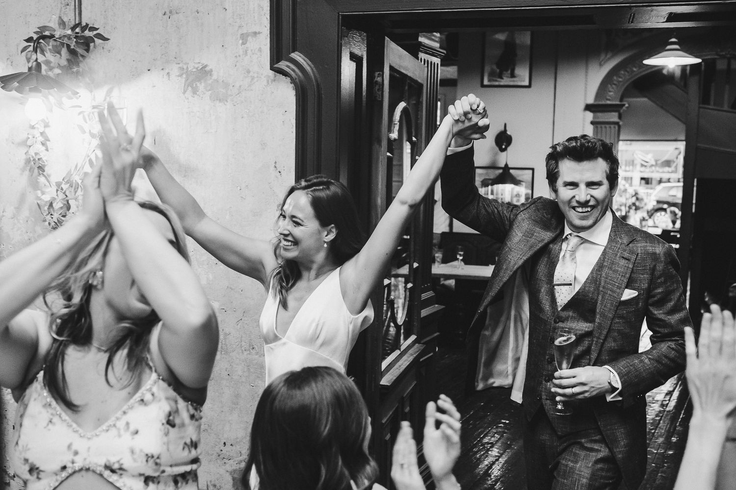Black and white candid shot of wedding celebration with raised arms in jubilation.
