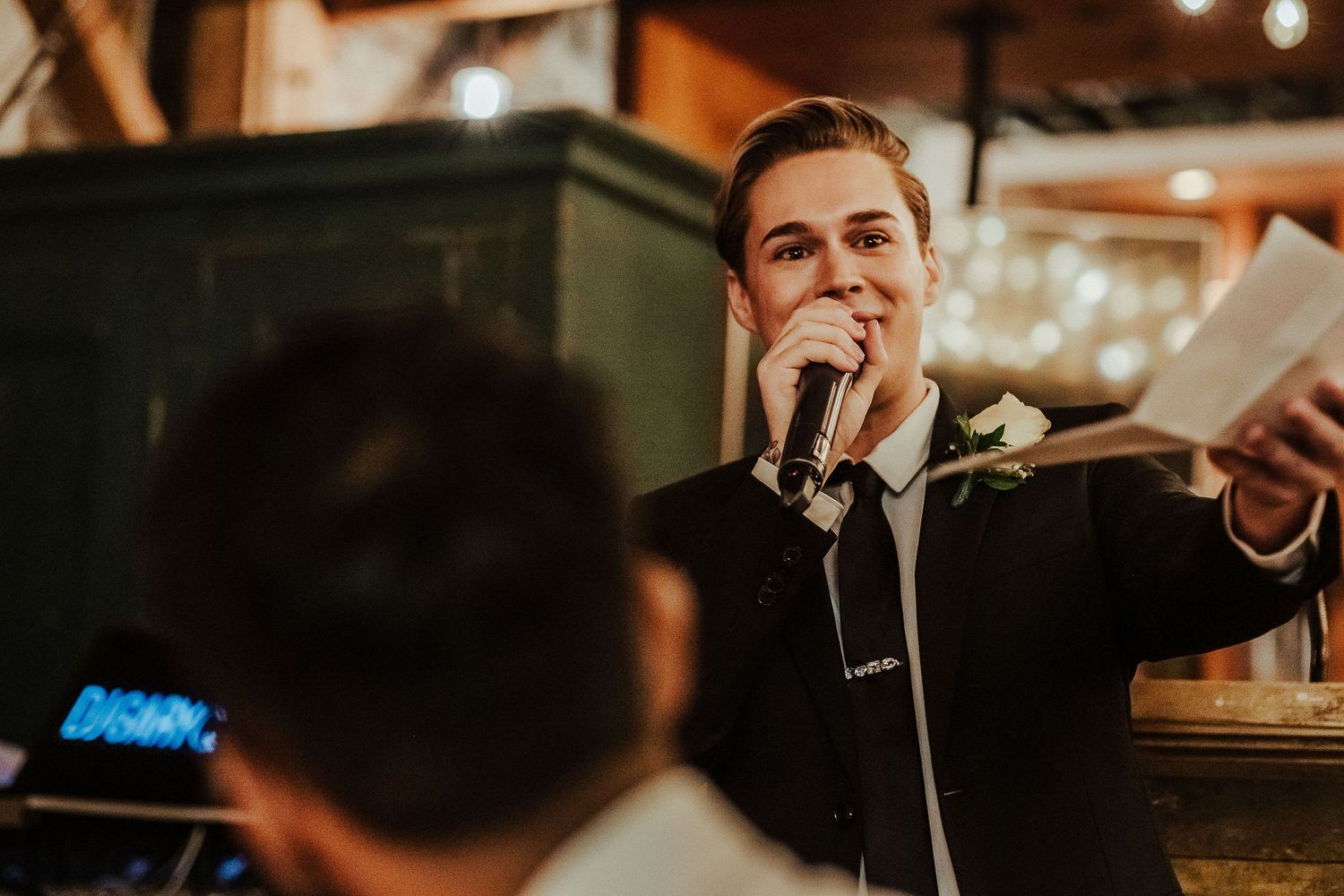 Warm lighting illuminates guests enjoying speeches at an evening celebration.