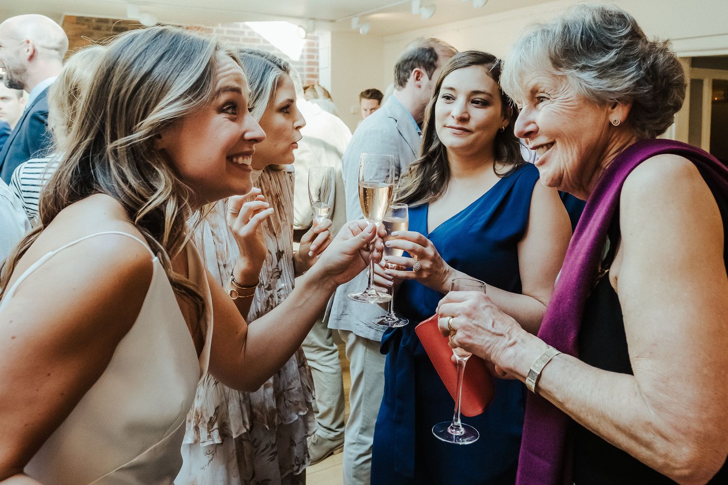 Guests laugh and share drinks during an elegant wedding reception.
