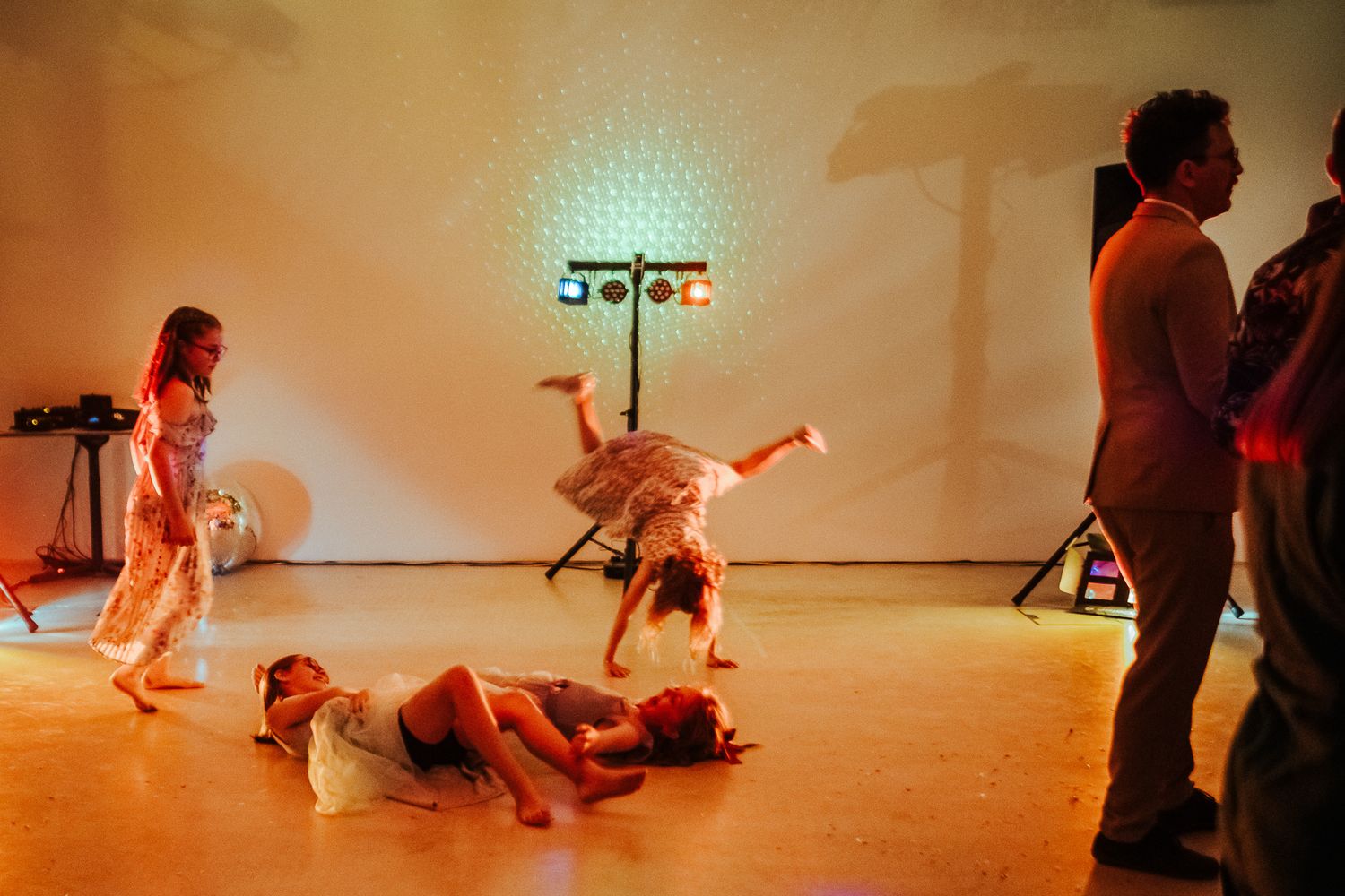 Dynamic dance moves and performers on stage with warm lighting at wedding reception.