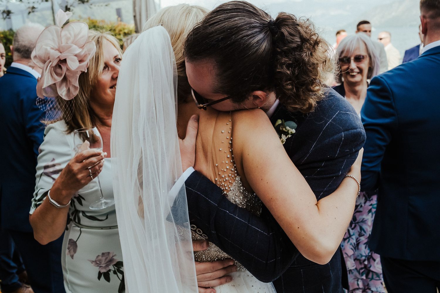 Emotional embrace shared between wedding guests during an outdoor celebration.