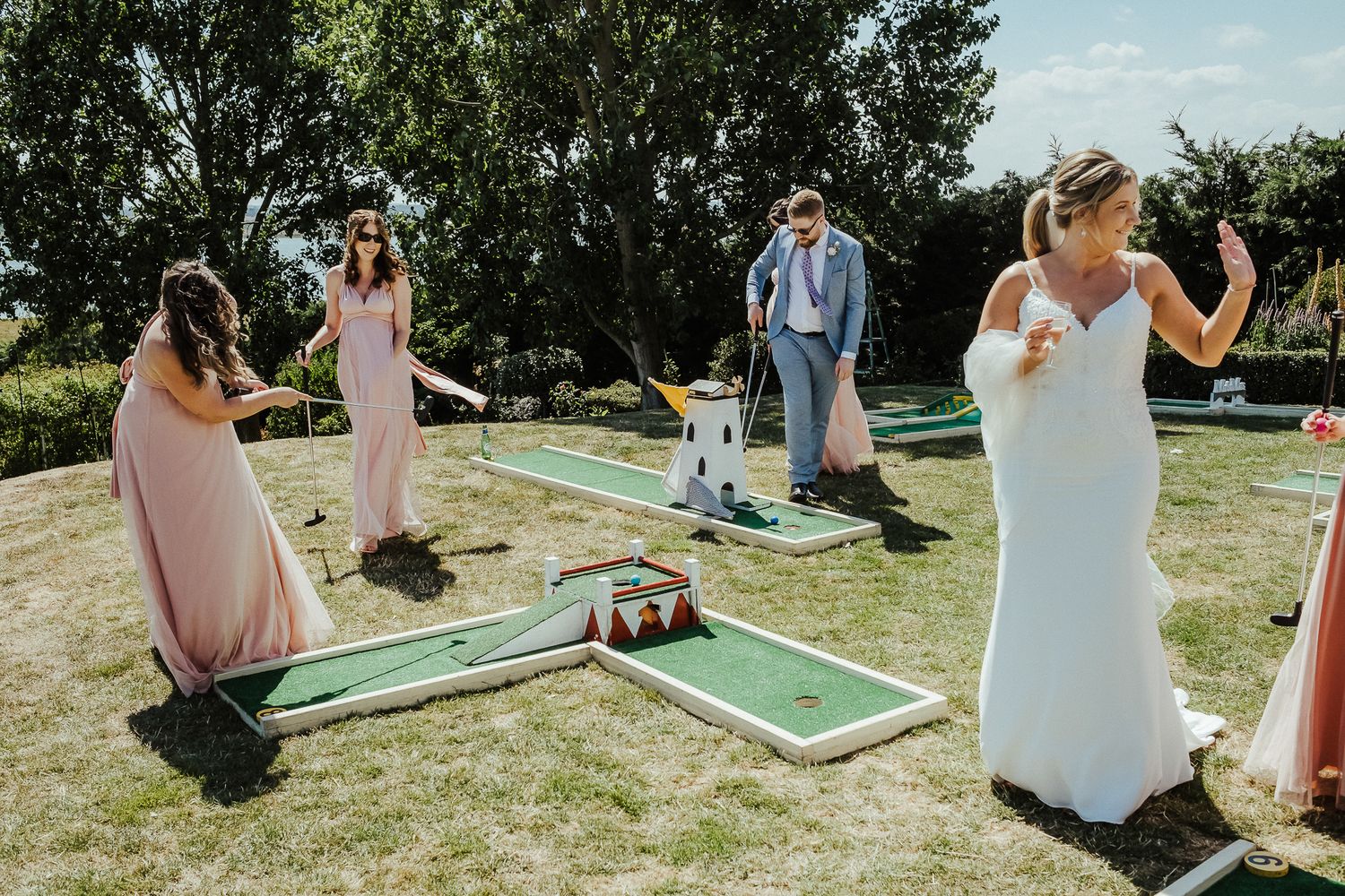 Wedding party enjoys mini golf games during outdoor celebration festivities.