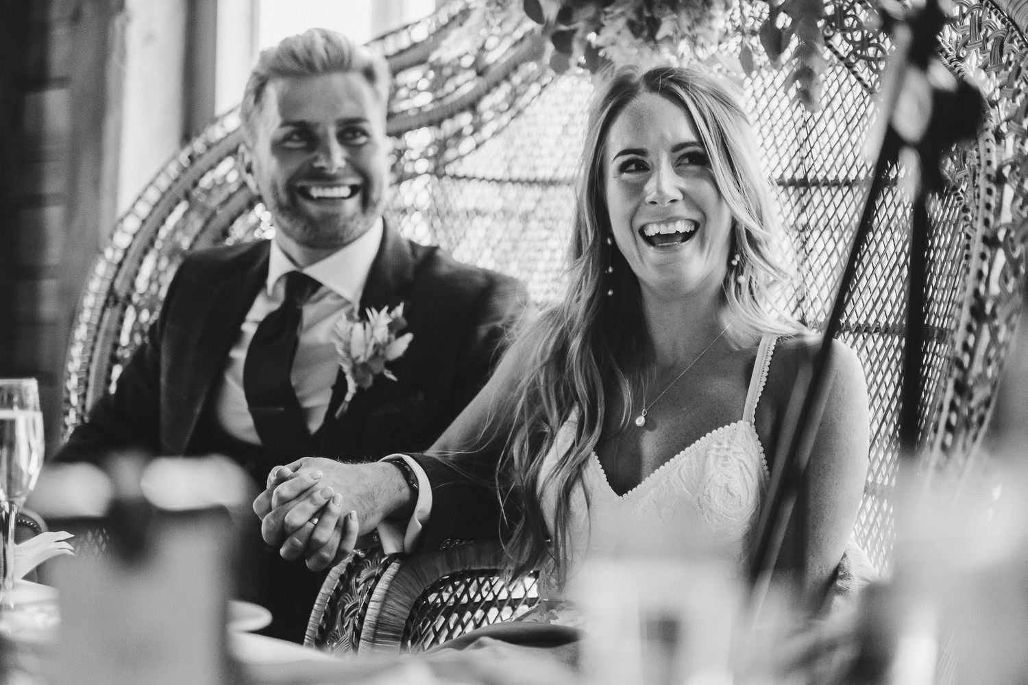 A candid moment of joy captured during wedding speeches at a reception.