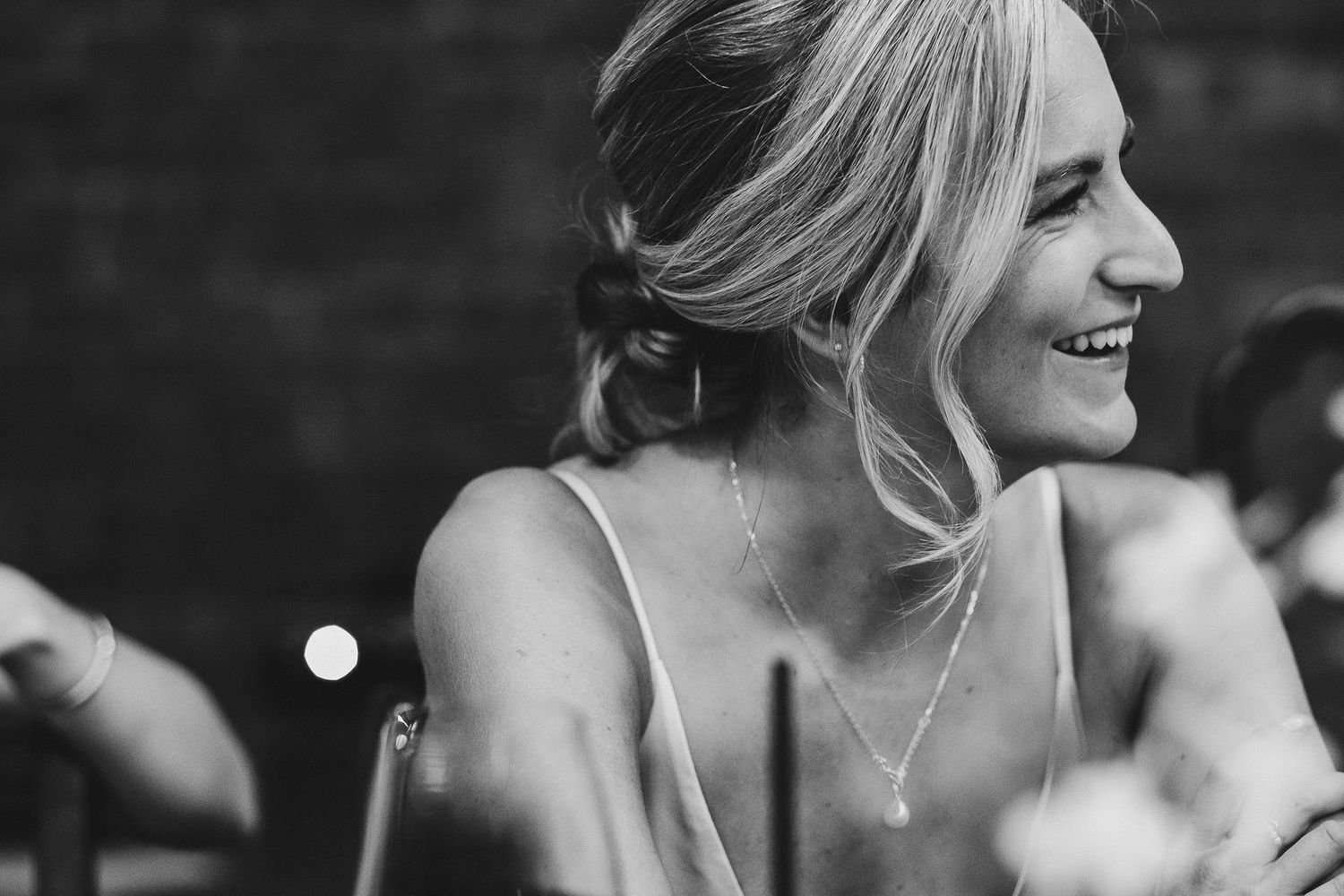 A candid black and white shot captures a joyful moment during a wedding celebration.