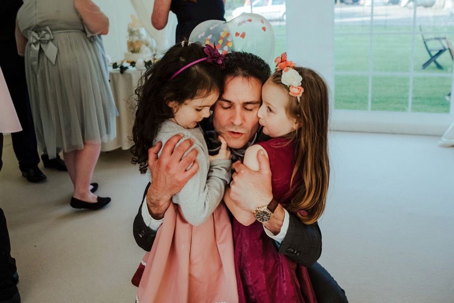An intimate family moment showing affection between three people during what appears to be a wedding celebration.