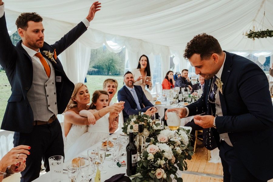 Wedding reception celebration moments with guests and couple inside an elegant white tent venue.