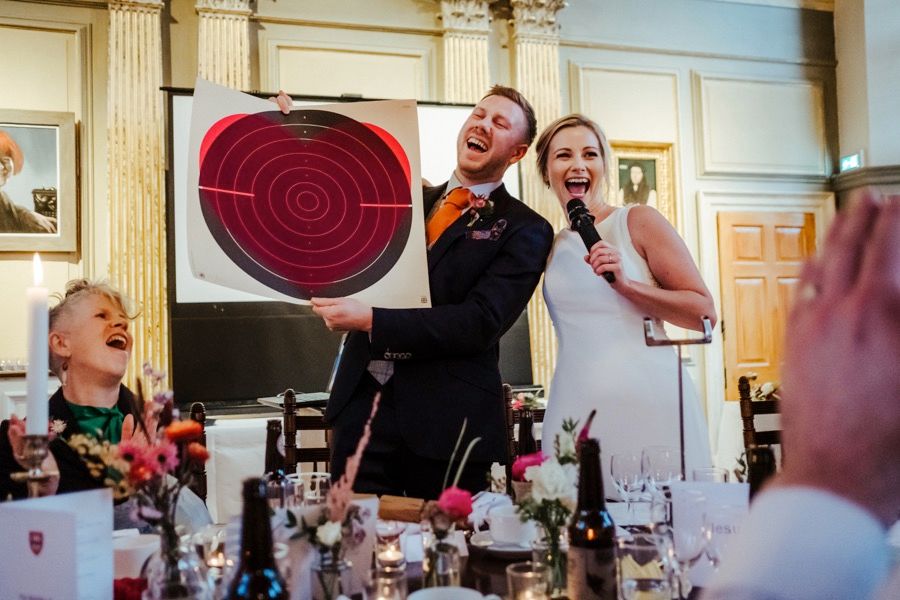 Wedding reception in an elegant hall with ornate gold columns and decorative lighting.