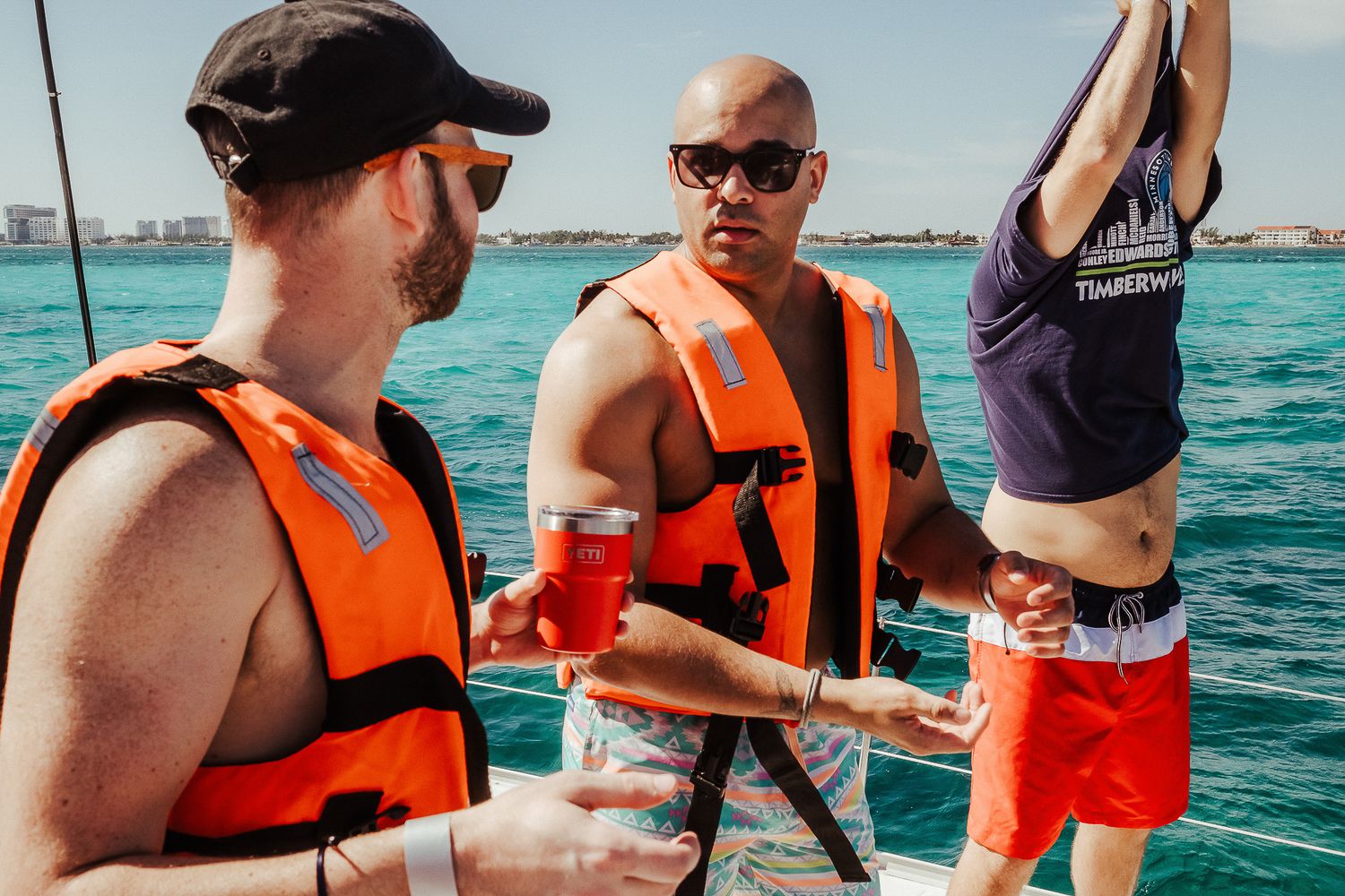 People wearing orange life vests enjoying a boat trip on turquoise waters.