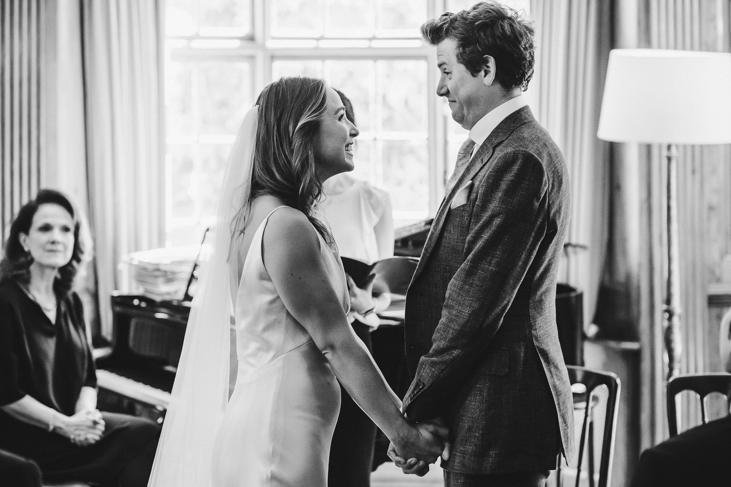 Black and white photo capturing emotional moment during indoor wedding ceremony.