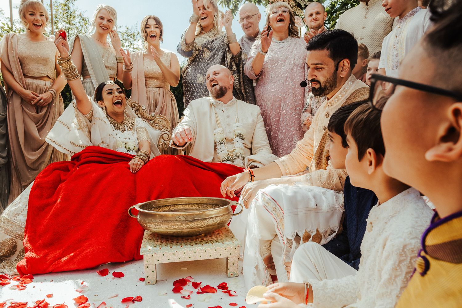 Wedding celebration showing couple participating in traditional ceremony with decorative red cloth and guests watching.