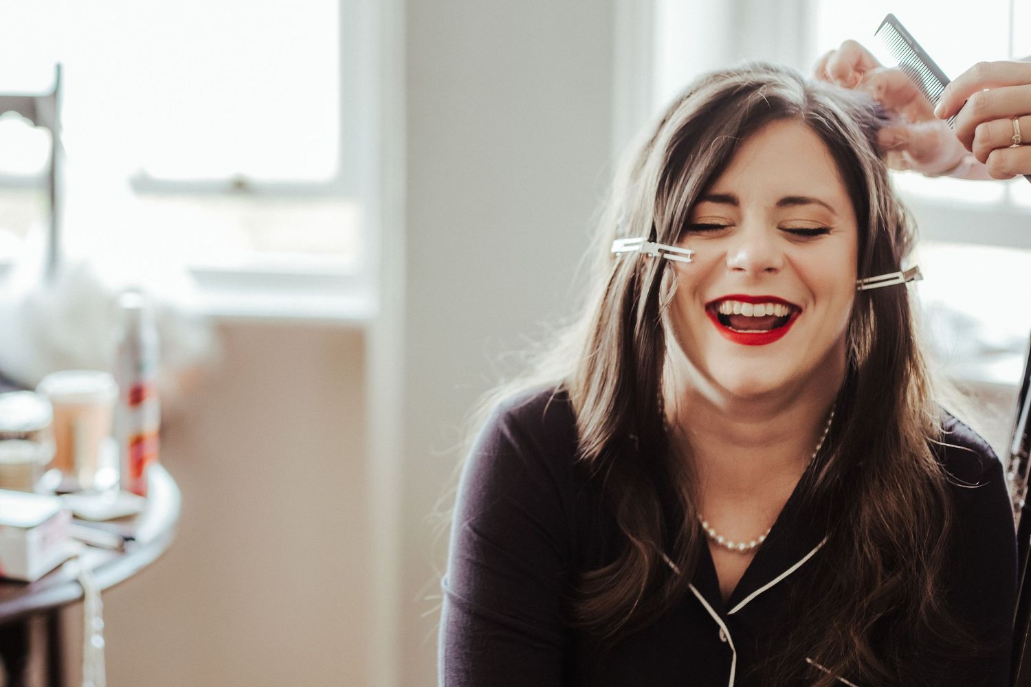 A candid moment of laughter during wedding day makeup preparation.