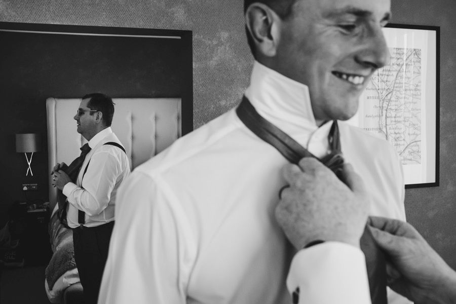 Classic black and white shot of formal attire preparation with tie adjustments.