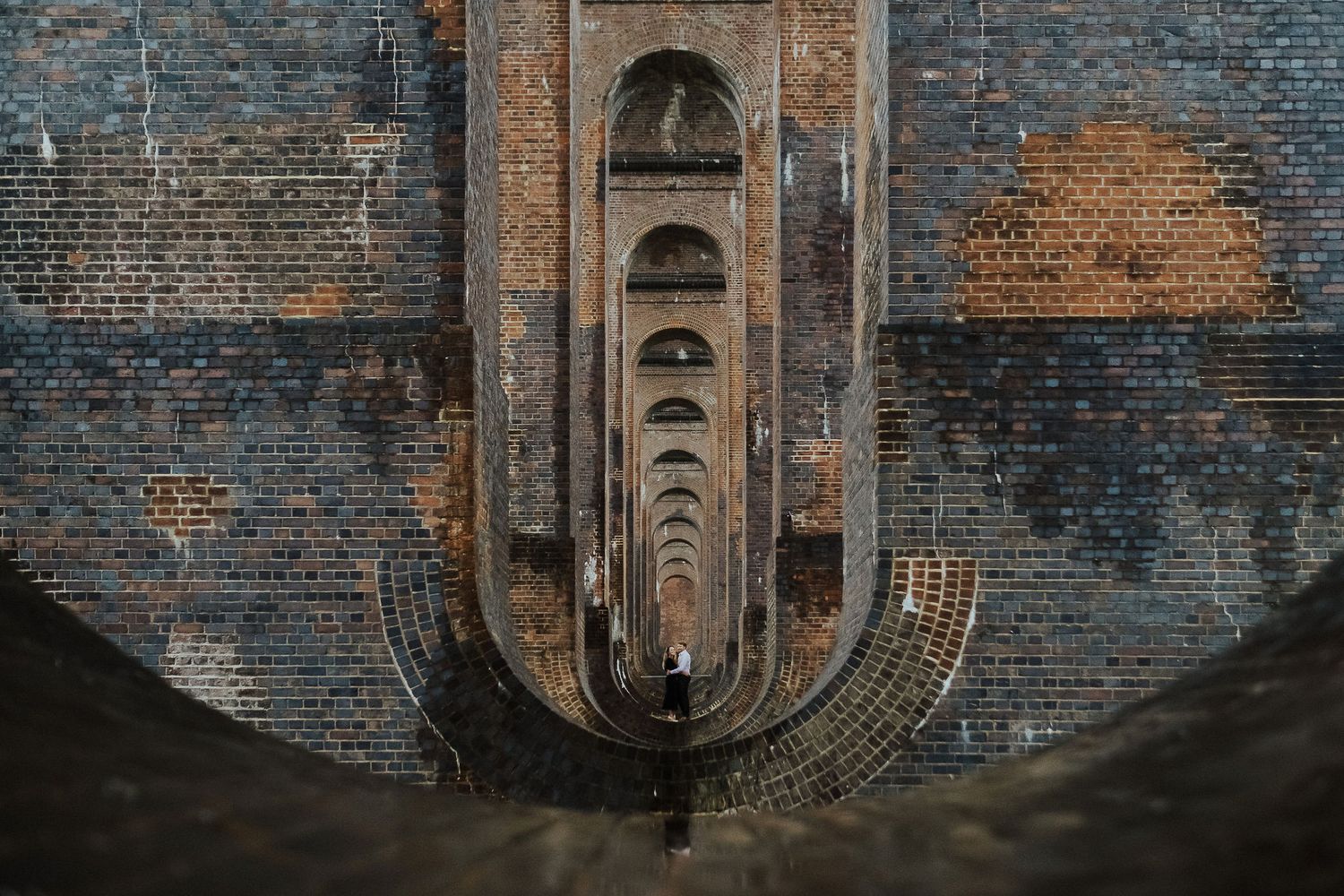 Architectural view of a symmetrical brick tunnel with repeating arched openings.