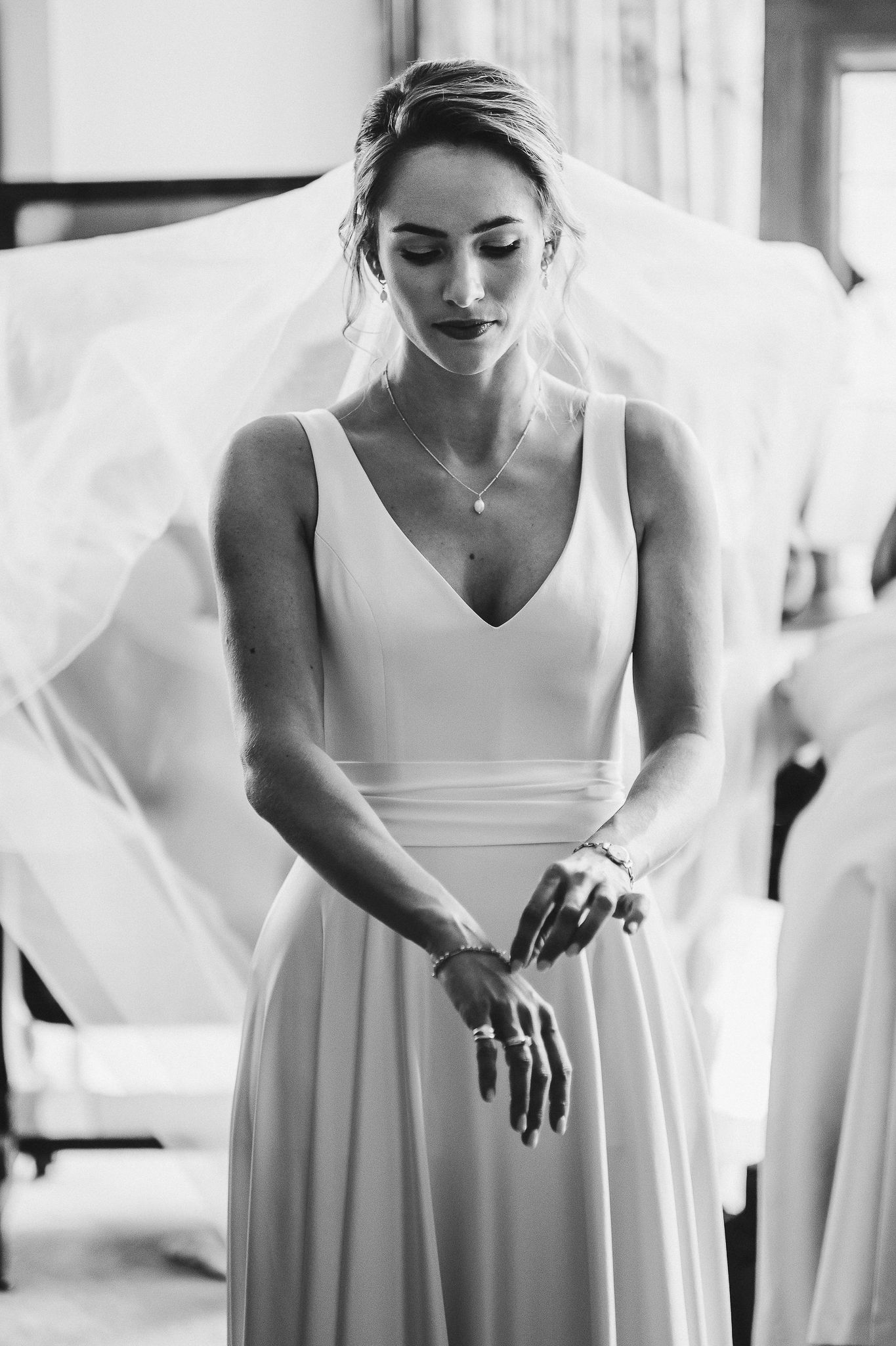 Black and white portrait of bride in classic V-neck gown with flowing veil.