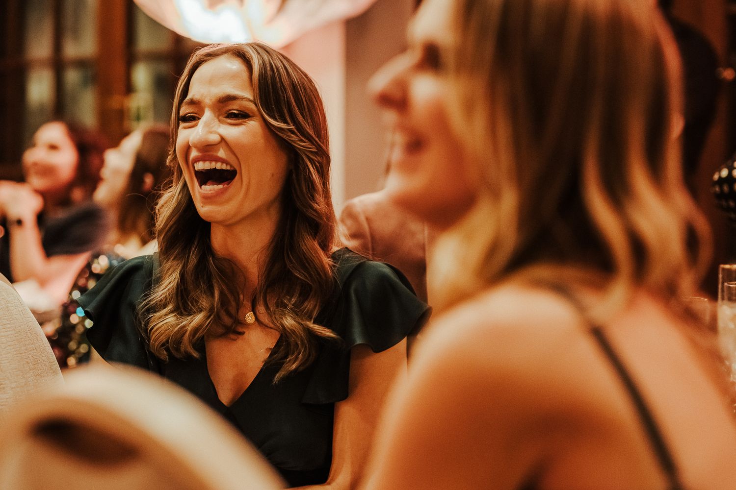 Candid moment of wedding guests laughing during reception celebration.