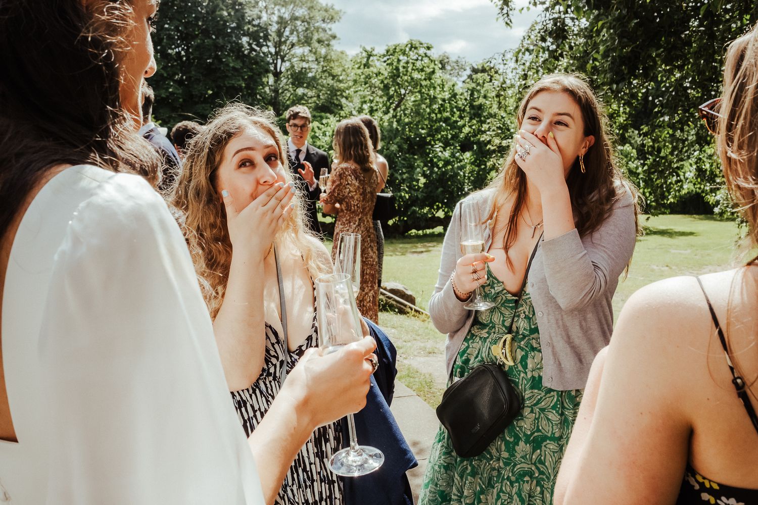 Wedding guests socializing in a sunny garden during a reception.