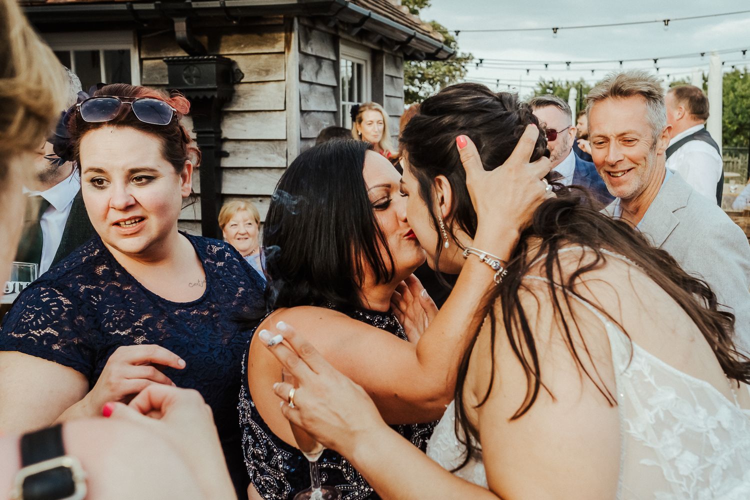 Candid emotional moment between wedding guests during an outdoor celebration.