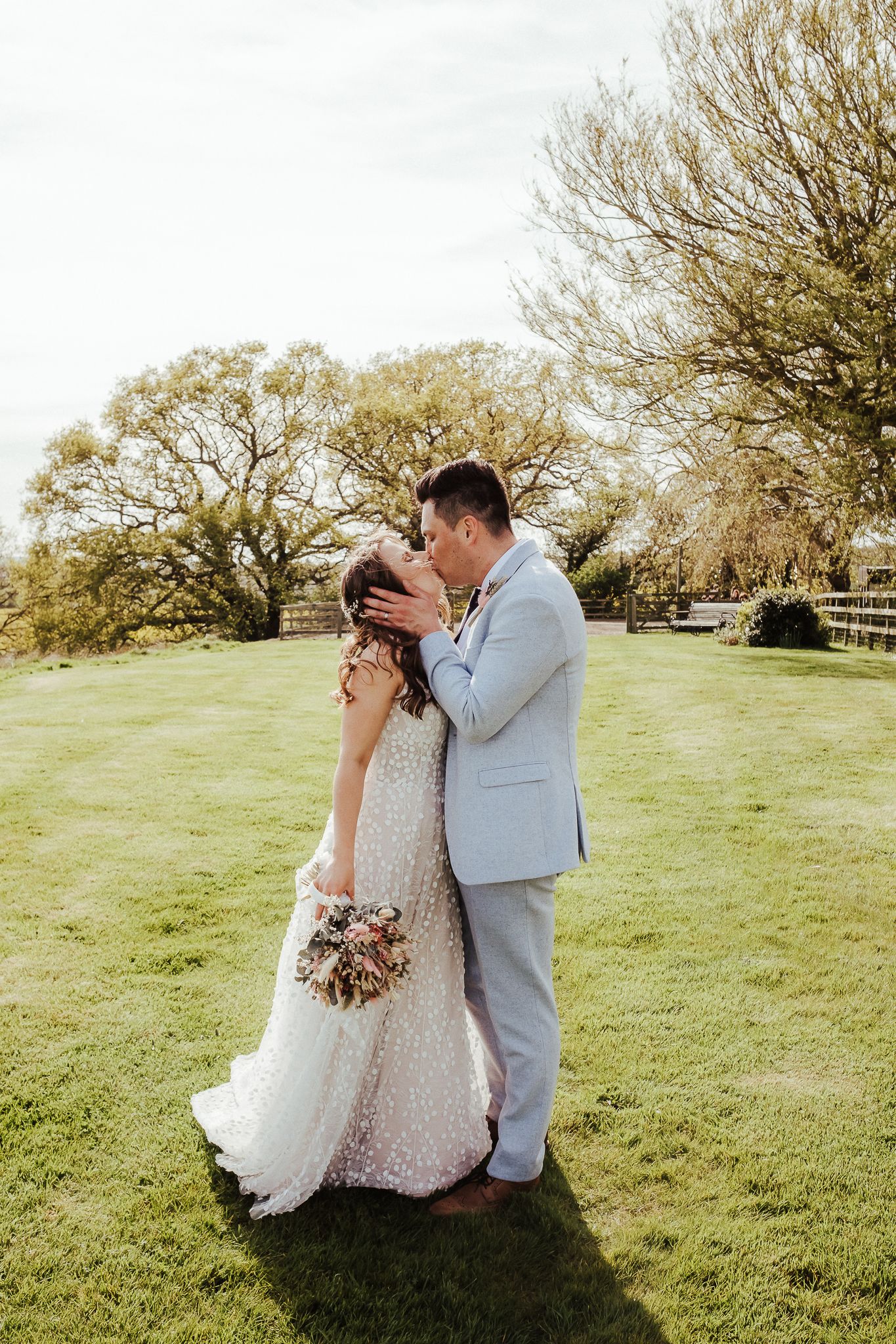 Romantic moment between newlyweds in sunlit garden setting.