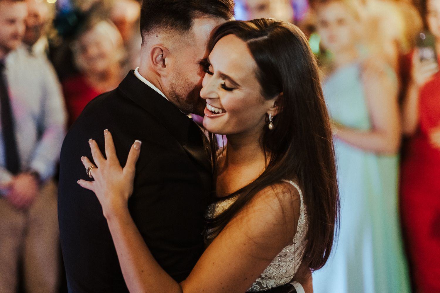 Wedding couple shares an intimate dance surrounded by colorfully dressed guests.