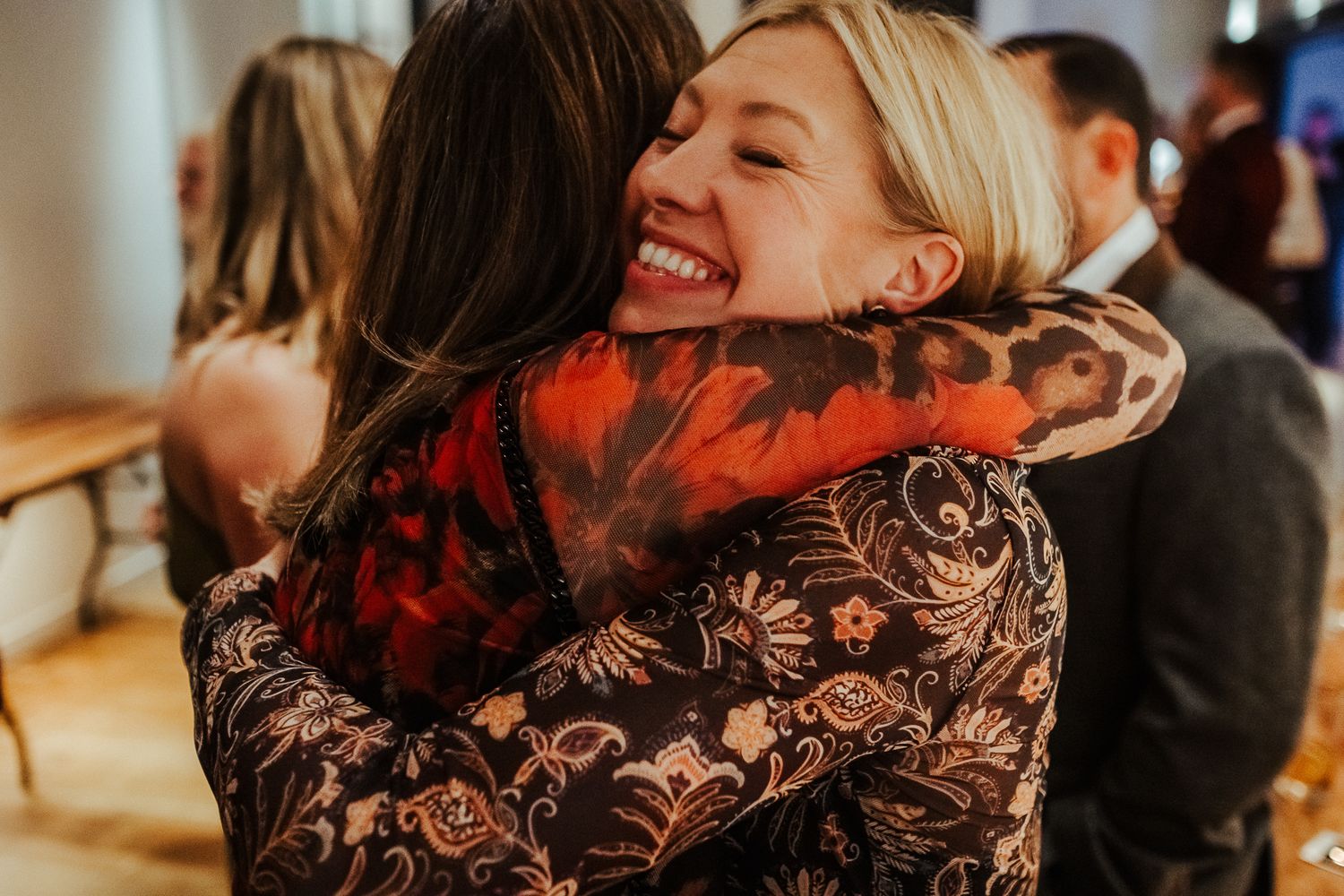 Two people sharing a warm embrace at an indoor celebration.