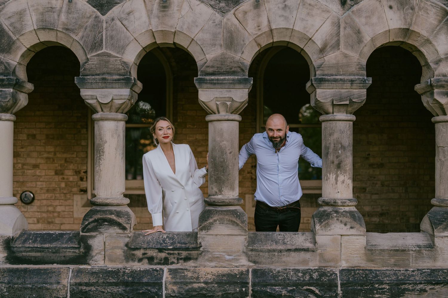 Playful couple portrait behind historic stone column arches in Toronto