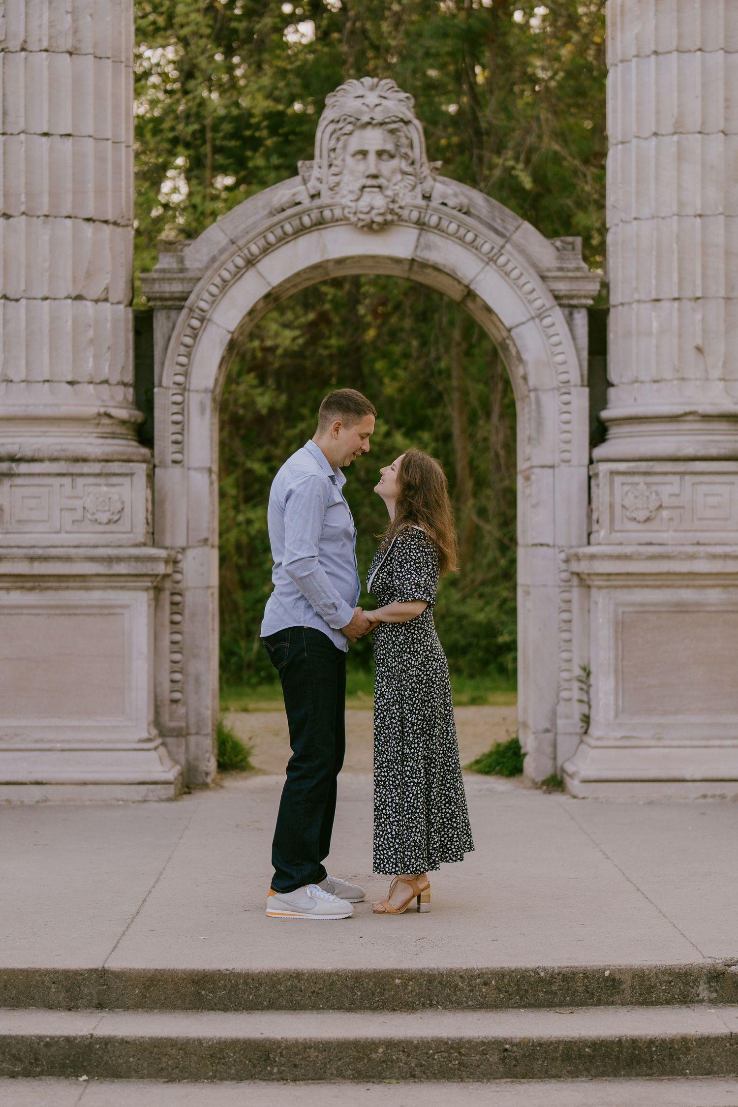 Couple holding hands in stone archway during engagement shoot in Oshawa, Ontario, available throughout Toronto and Durham region