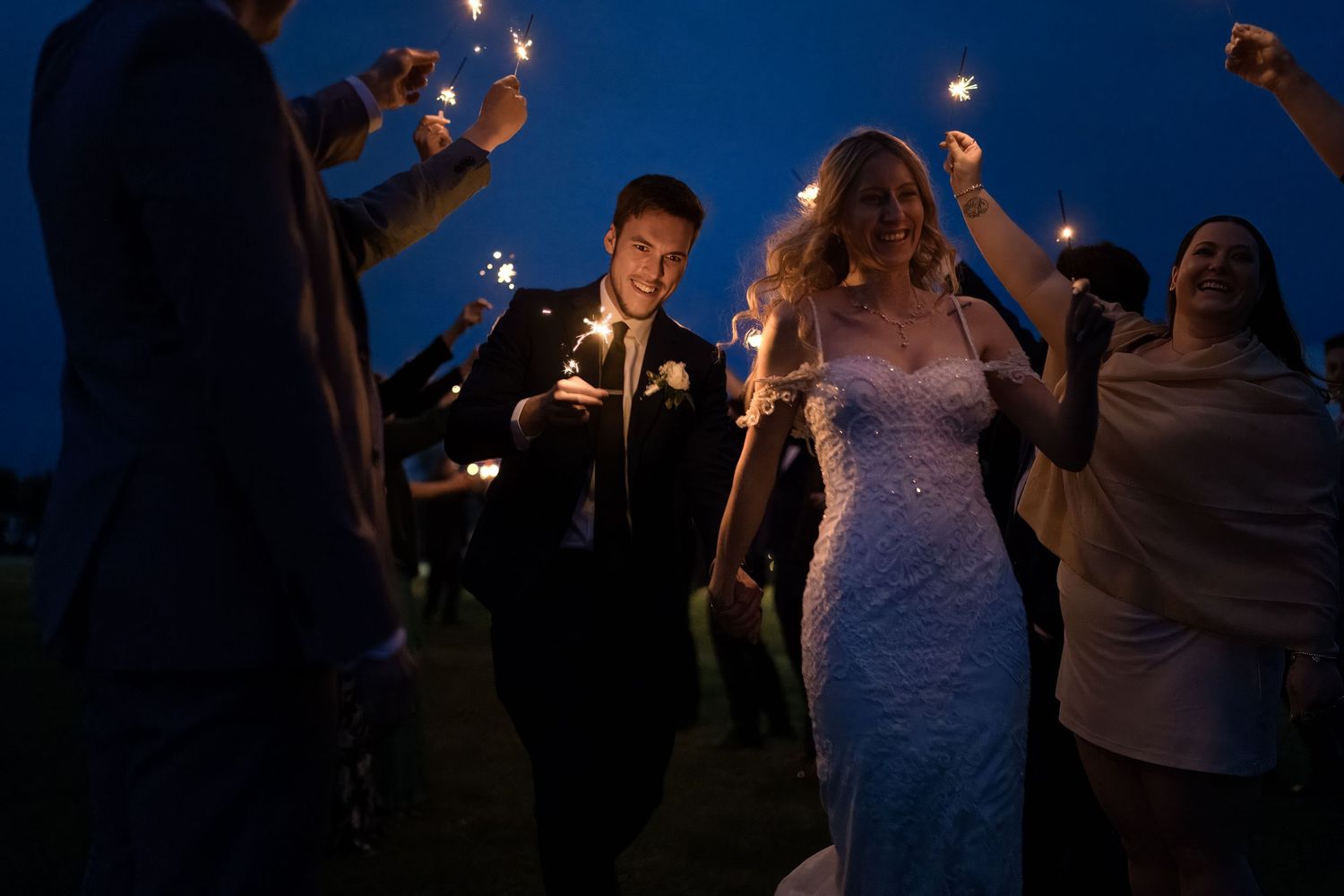 Bride and groom walking through sparkler tunnel during evening wedding exit in Oshawa, Ontario