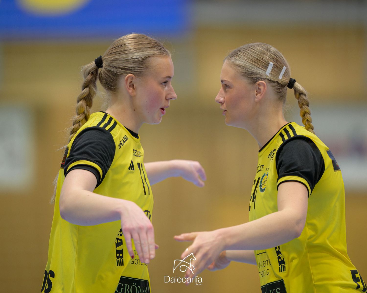 Two athletes in yellow uniforms communicate during a match.
