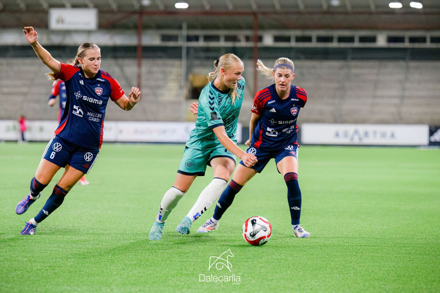 Soccer players compete for possession of the ball during a match on an artificial turf field.