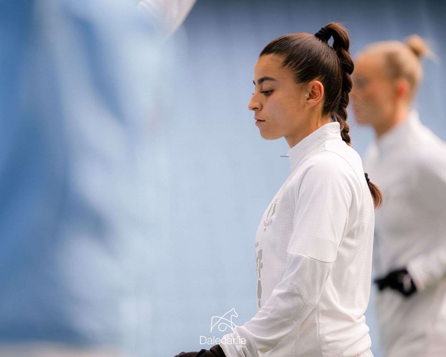 A martial artist in white uniform stands in contemplative pose during karate practice.