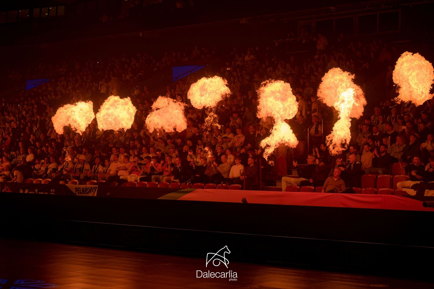 Multiple fiery explosions create a dramatic pyrotechnic display across a darkened stage during a live performance event.