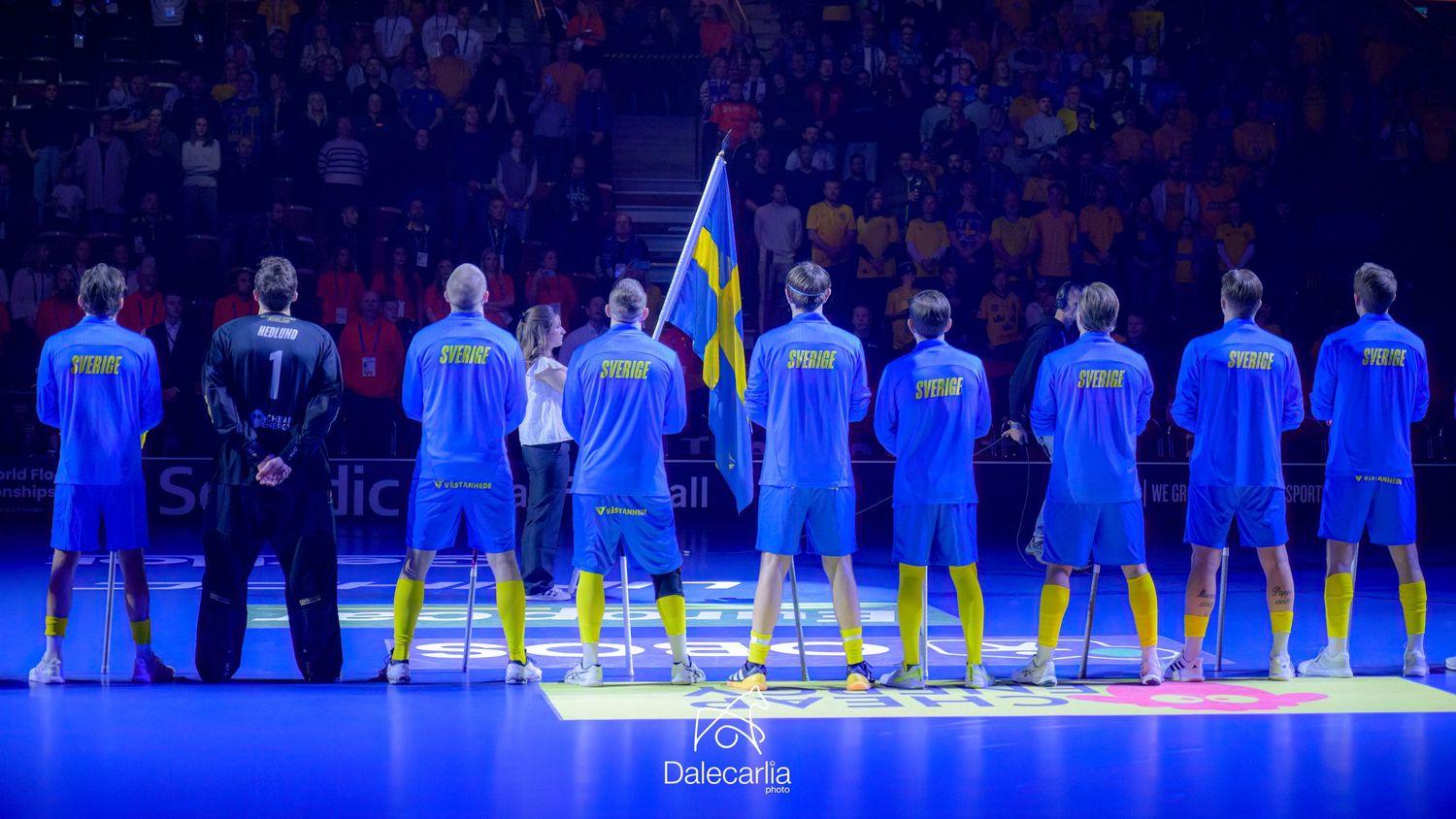 Basketball team stands in formation during pre-game lineup wearing blue uniforms under dramatic arena lighting.