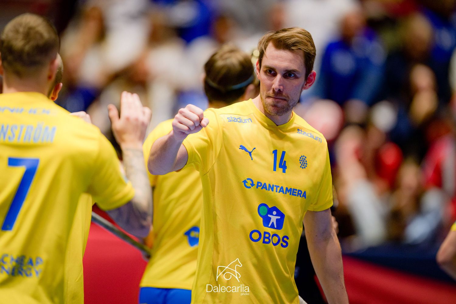 Handball player in yellow Puma jersey celebrating during competitive match.