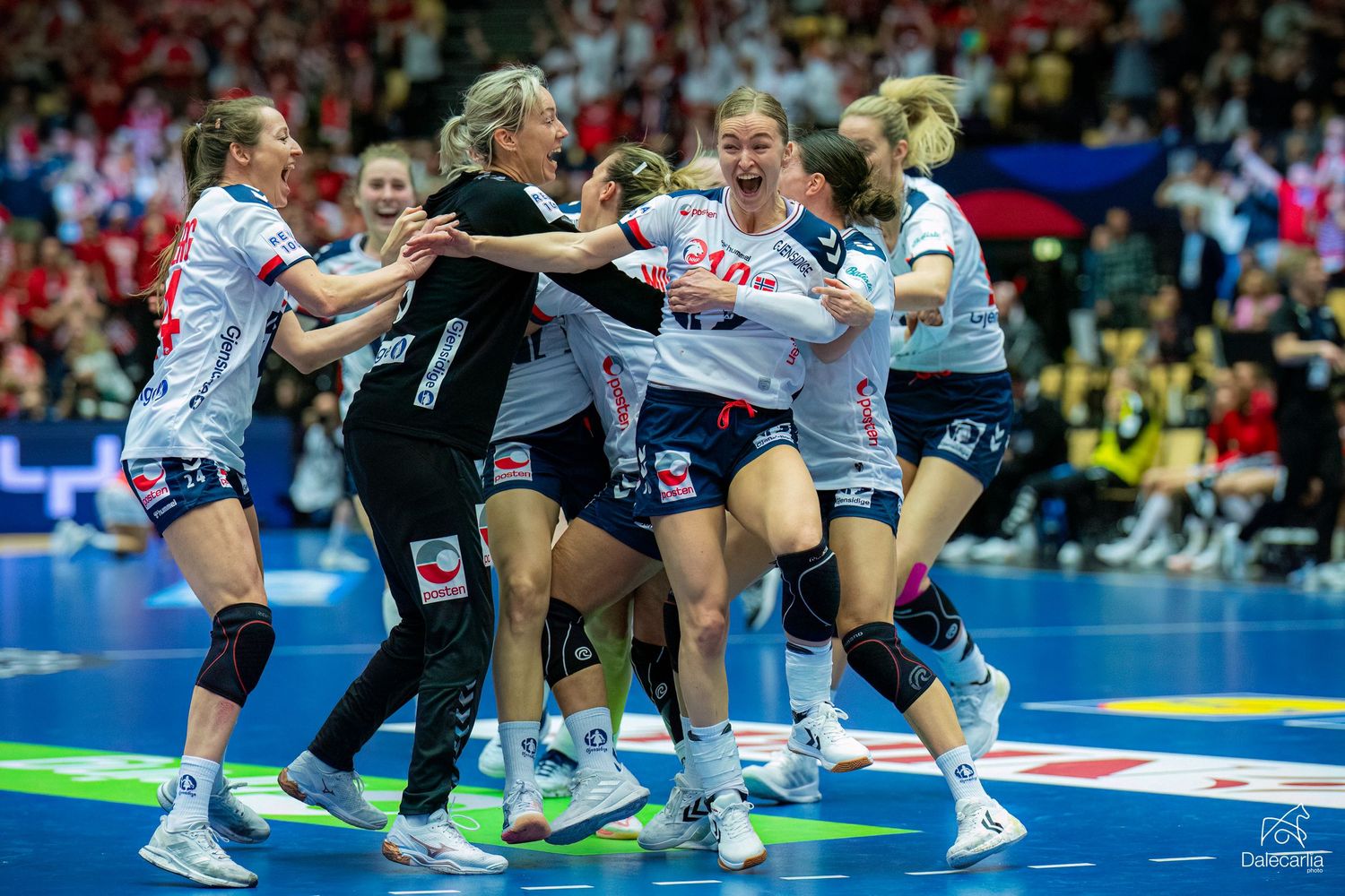 Female handball players celebrate together on the court during an intense competitive match.