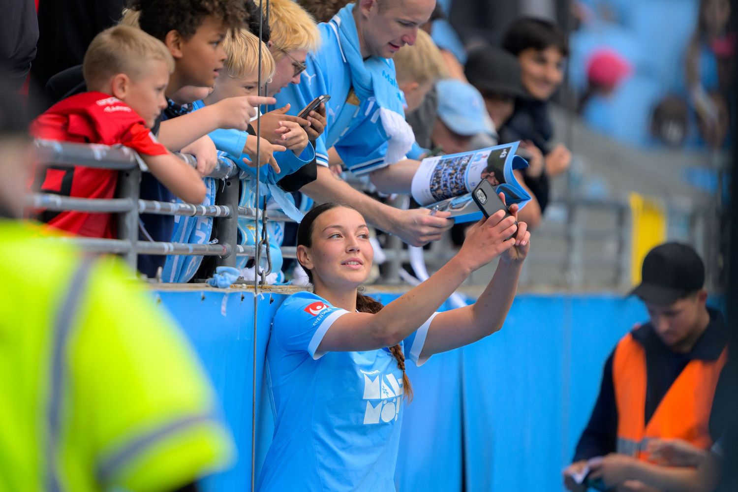 Soccer players celebrate with fans in the stands after scoring during a match at a stadium.
