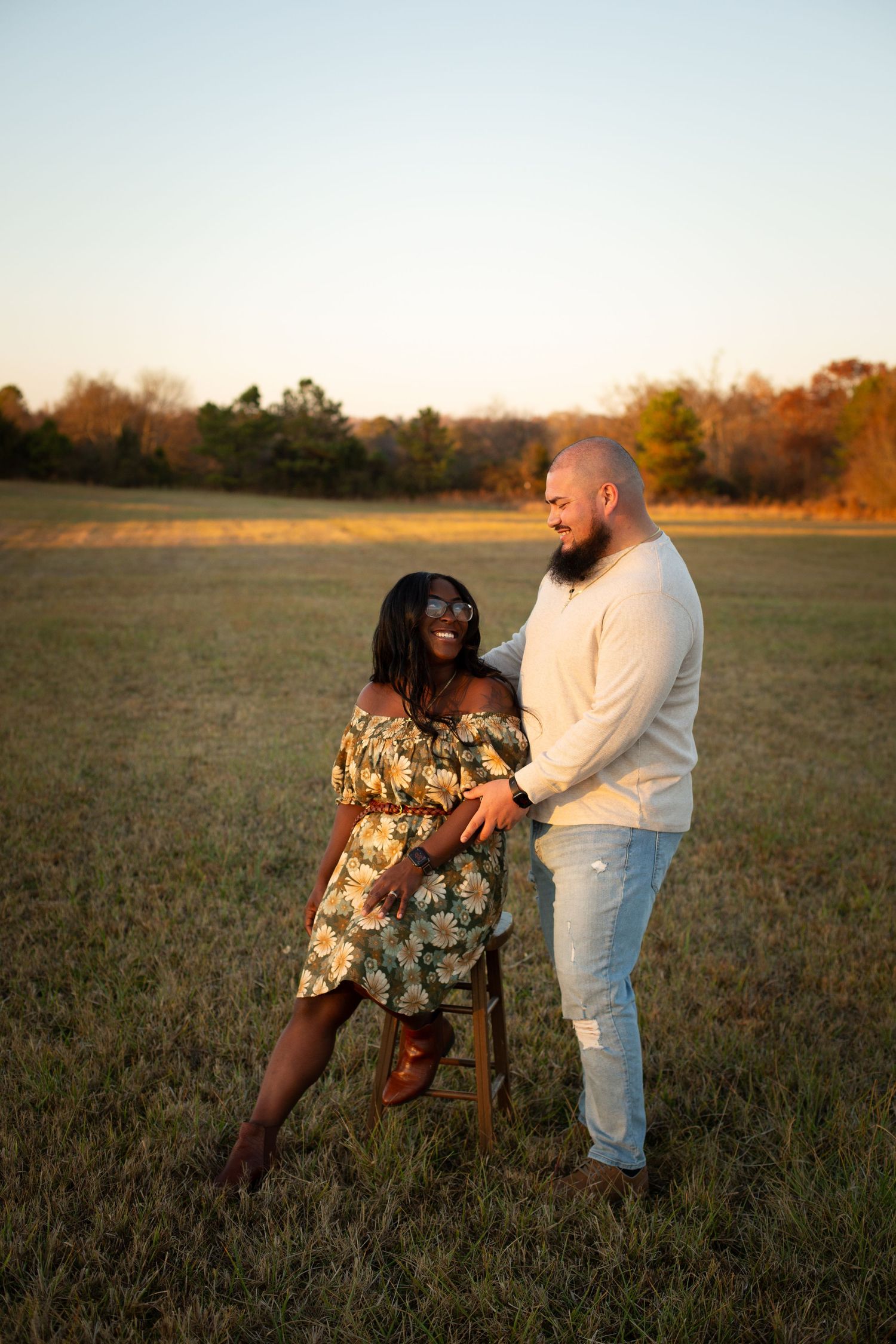 Couple shares intimate moment in open field during golden hour sunset.