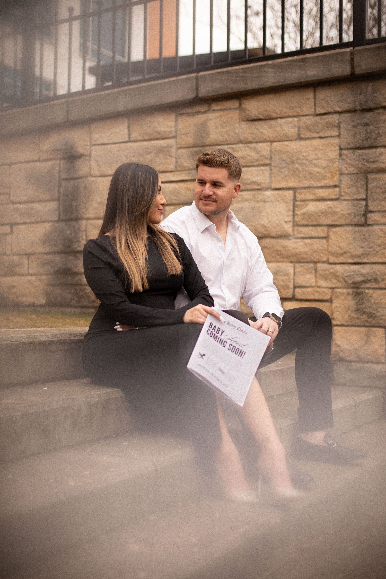 Couple sitting on stone steps sharing a document in an outdoor urban setting.