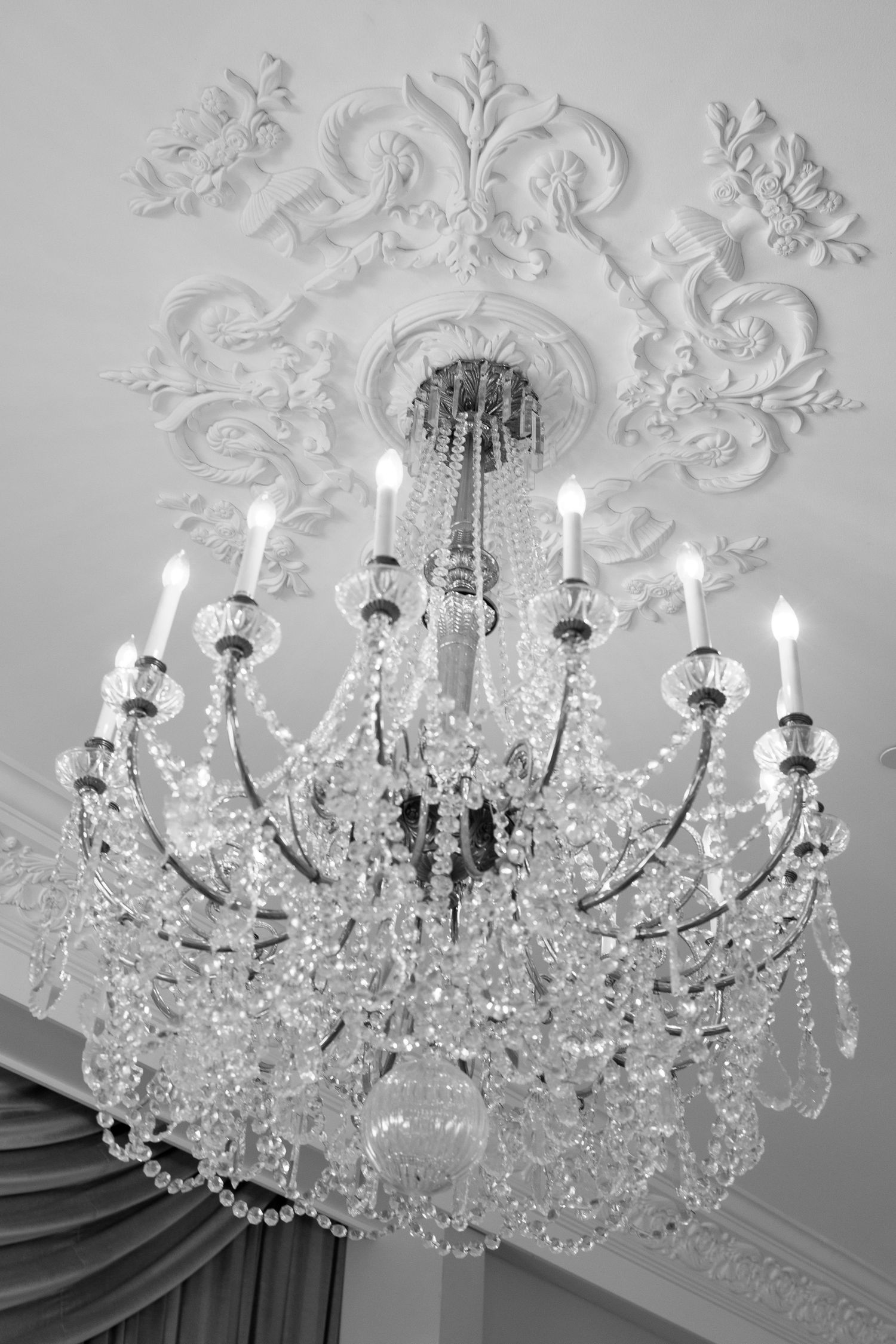 An ornate crystal chandelier with multiple tiers hangs from an elaborately decorated white ceiling medallion.