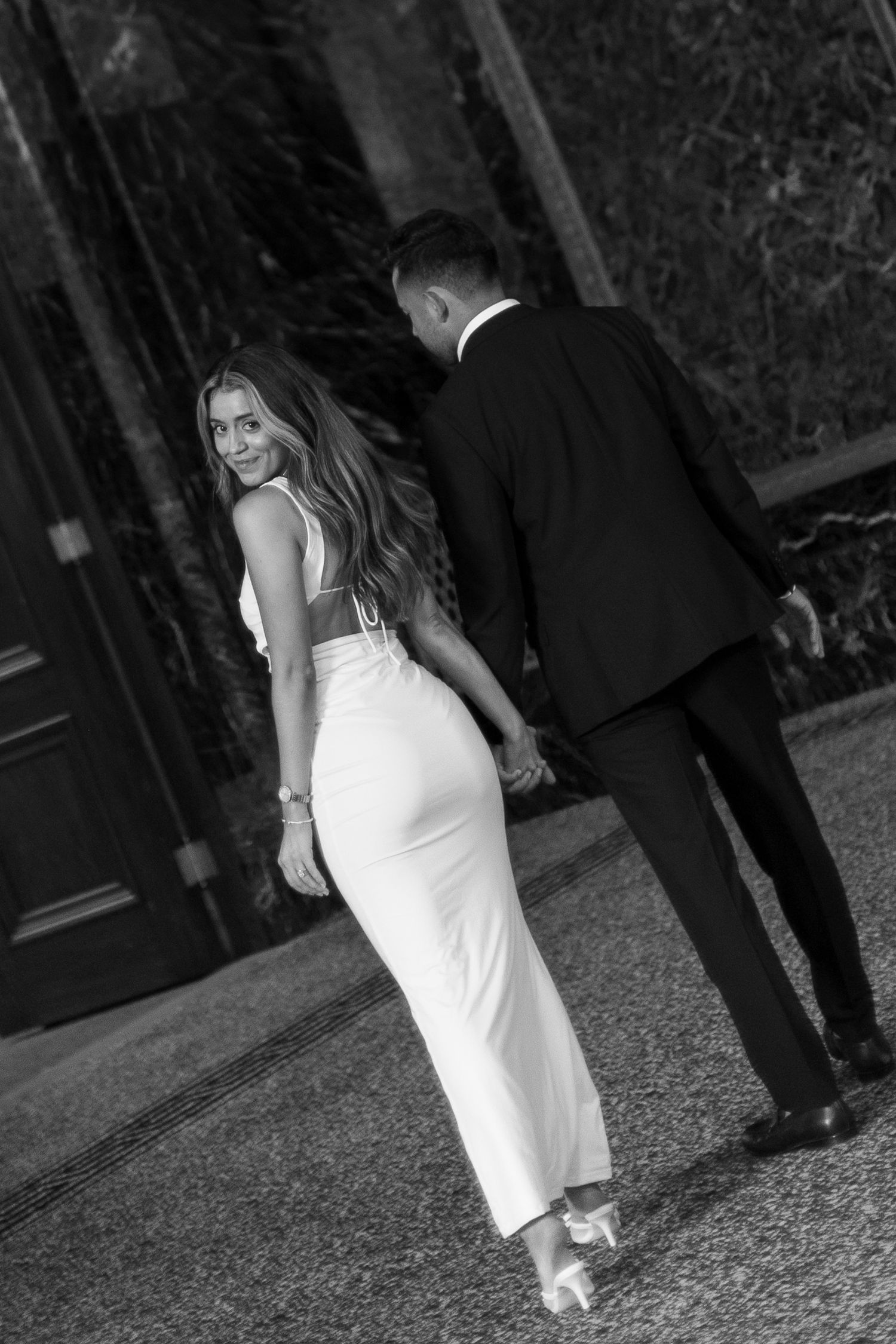 Couple poses in formal attire against dark doorway background.