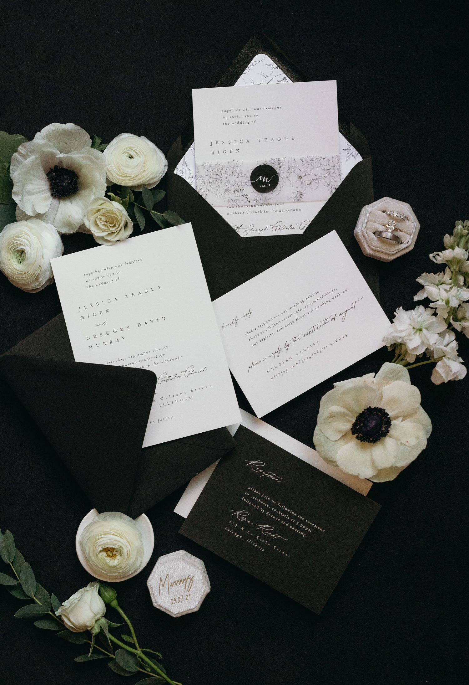 Wedding stationery flat lay featuring black and white invitations with delicate floral accents.