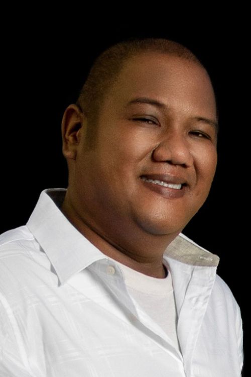 Professional headshot of co-owner in white shirt against dark background.