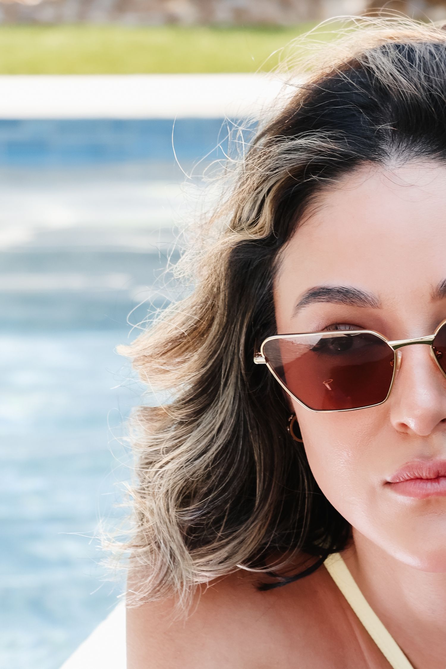 Stylish geometric sunglasses shown in beachside portrait series.