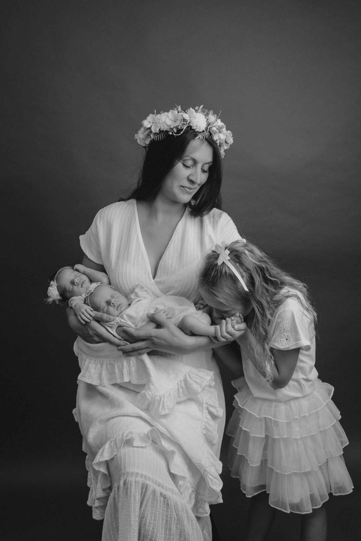 Ethereal black and white portrait of family in flowing white dresses with flower crowns.