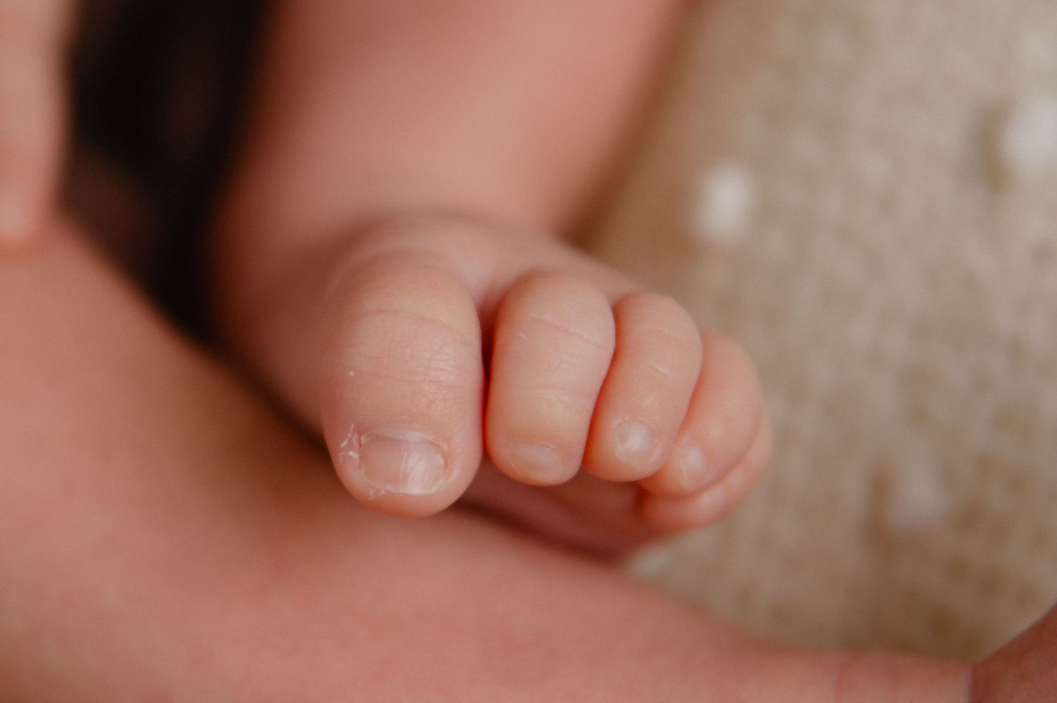 Close-up macro shot of tiny newborn baby toes and fingers.